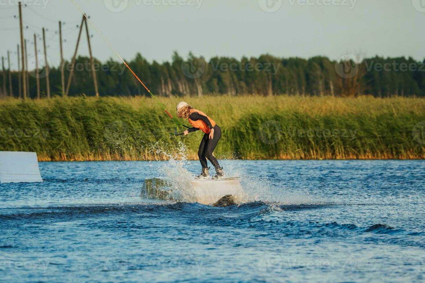 Wake boarding female sportsman girl jumping high wake boarding raley trick with huge water splash in the cable park photo