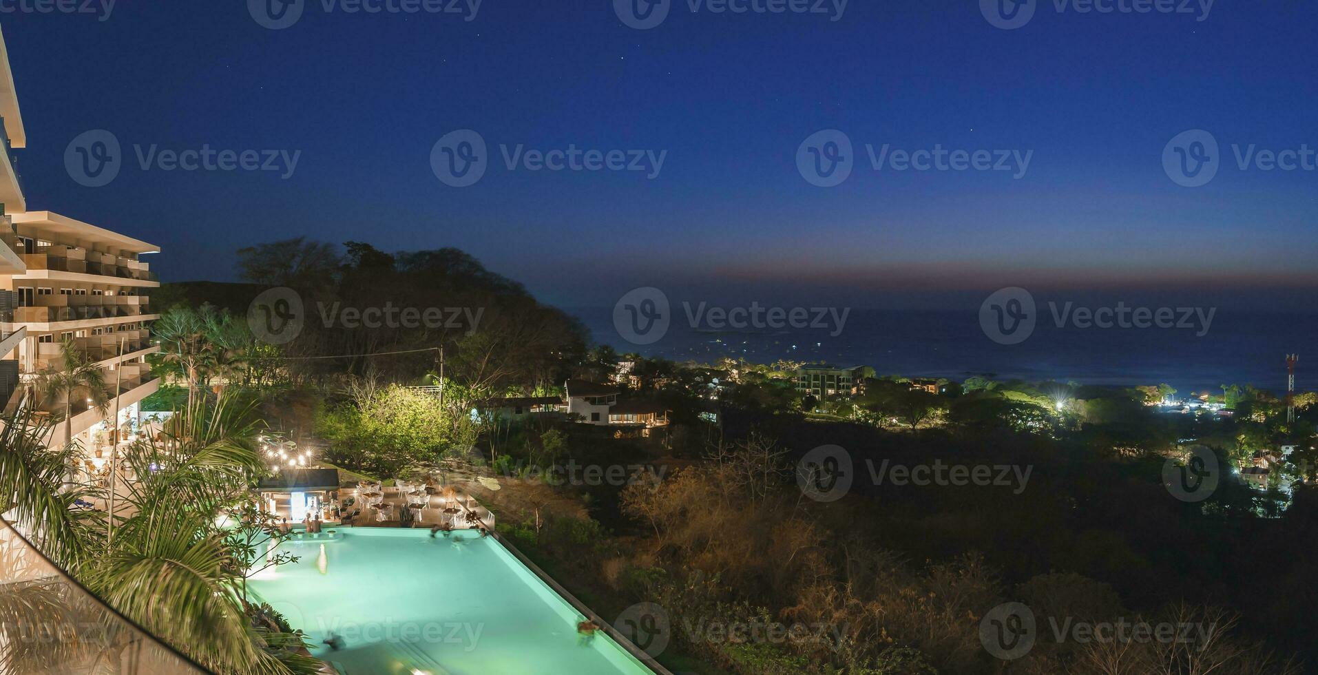 Illuminated luxury resort with tourists in swimming pool at costa rica photo
