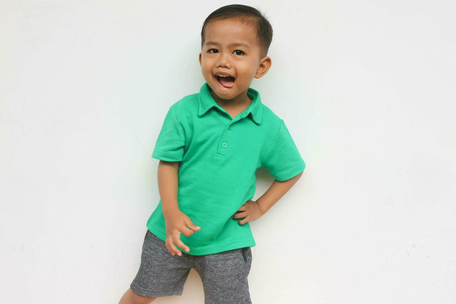 retrato de un contento pequeño asiático chico mirando a cámara mientras gritos en el blanco antecedentes foto