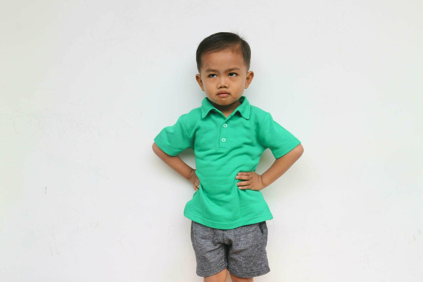 Portrait of a serious little Asian boy who looks unhappy, isolated on the white background photo