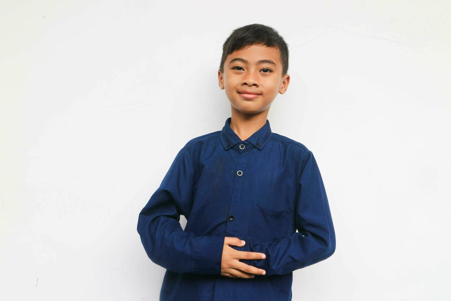 Smiling boy in blue shirt looking at the camera while put hands on the comfort belly photo