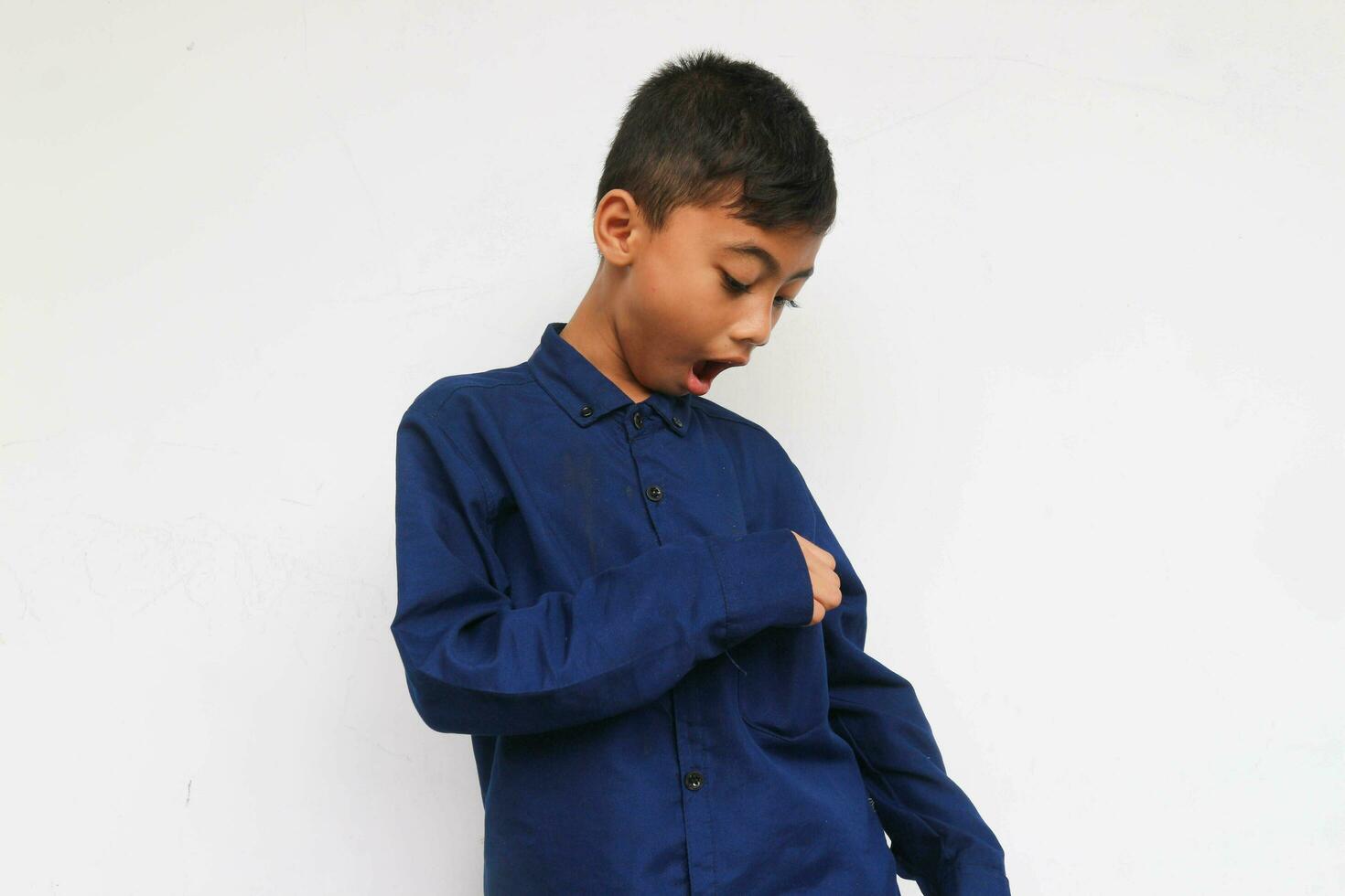 Surprised boy looking on to his pocket on a shirt , looks he found something. Isolated on white background photo