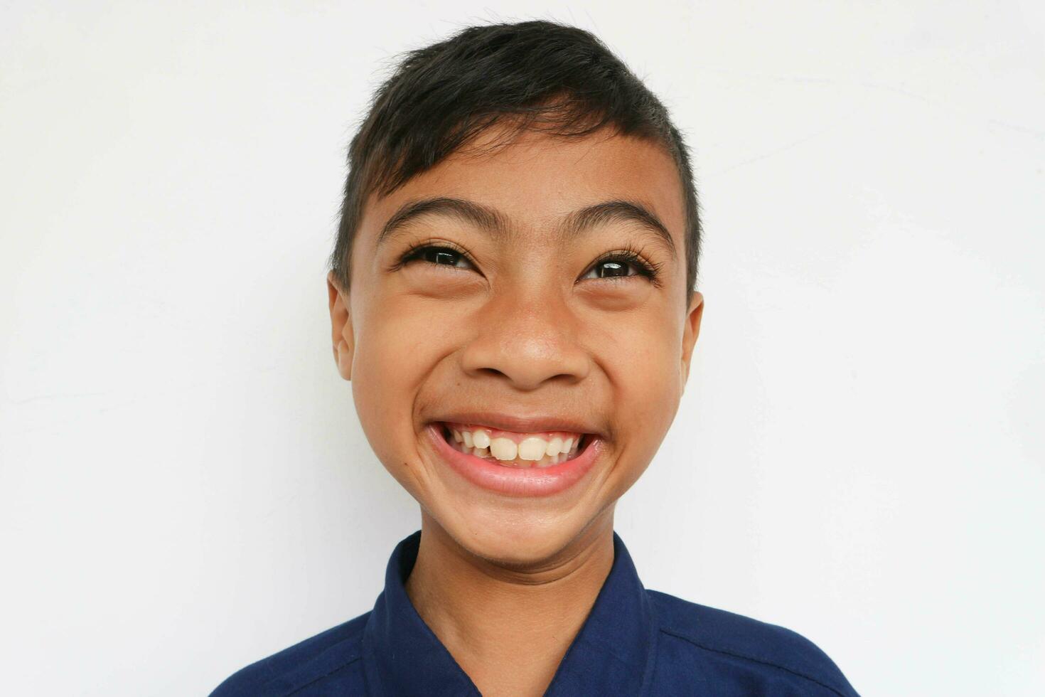 Close up of Cheerful little boy in express funny face, isolated on white background. A 10 years old boy making a funny face. photo