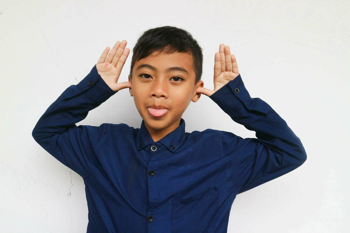Cheerful little boy in express funny face, isolated on white background. A 10 years old boy making a funny face. photo