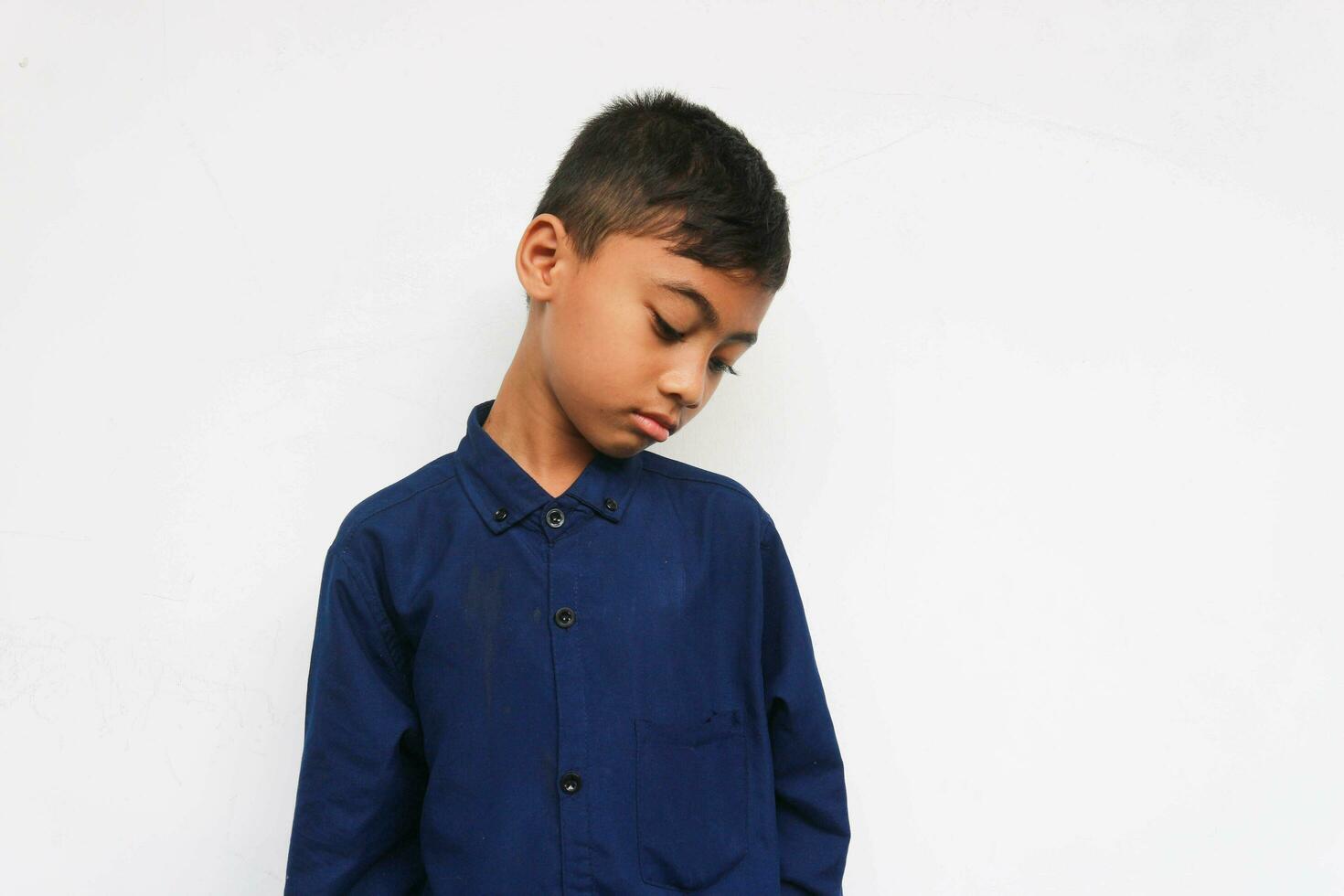 Sad boy wearing blue shirt isolated on white background photo