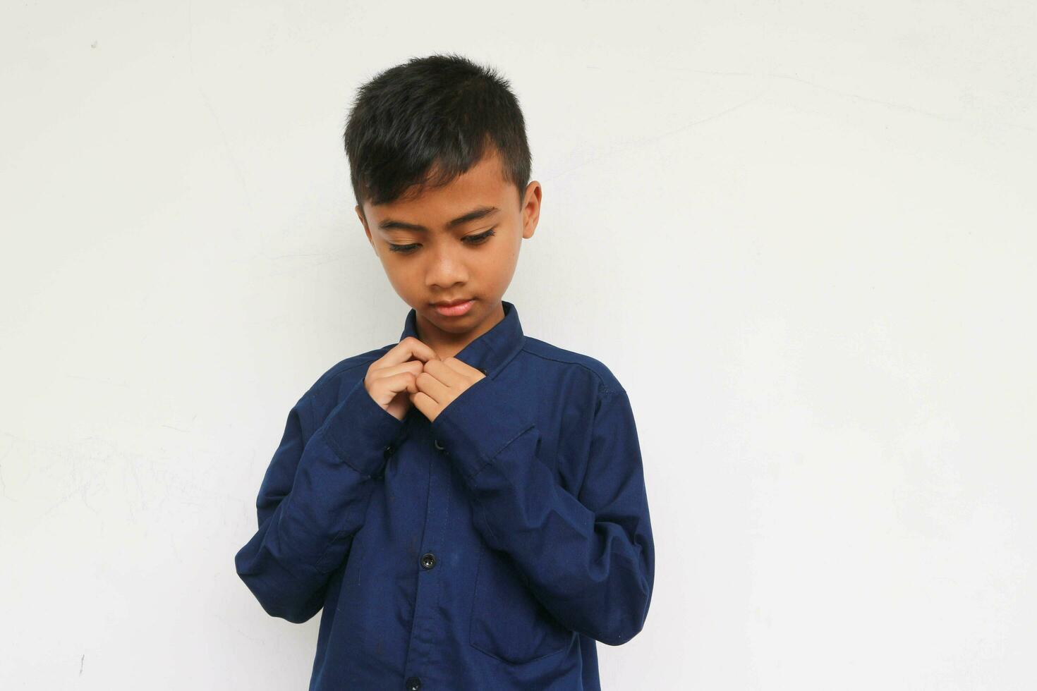 Sad boy wearing blue shirt isolated on white background photo