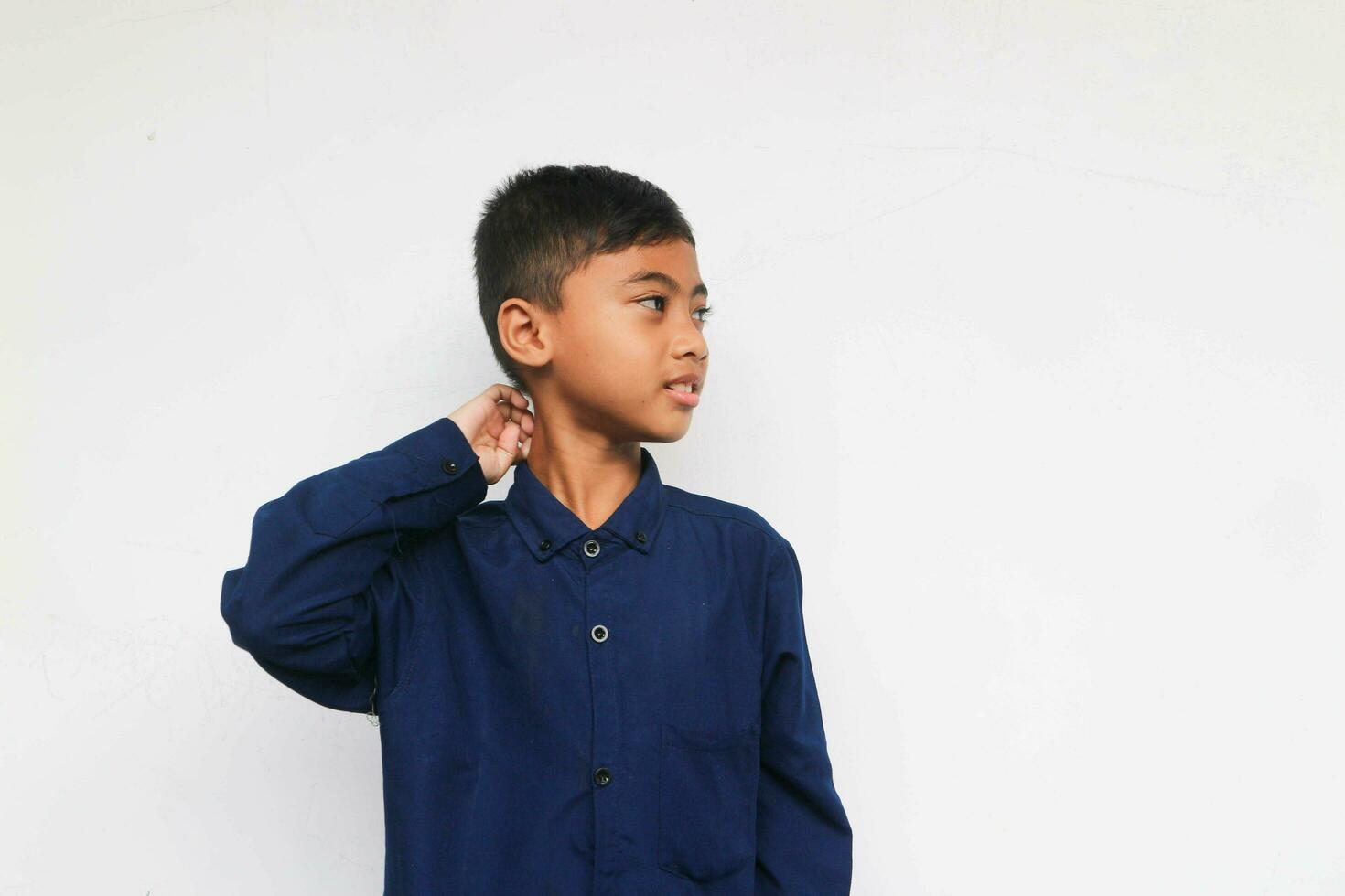 Cute bewildered boy in blue shirt looking at something with smile isolated on the white background photo