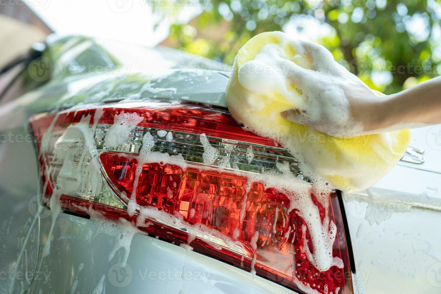 female hand with yellow sponge washing car photo