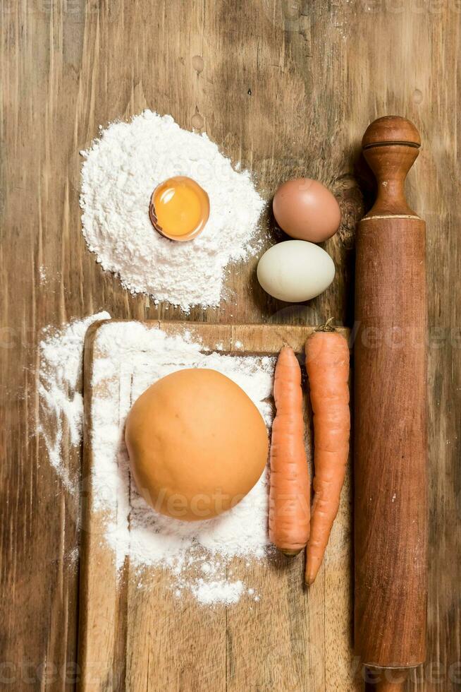 Orange carrot noodle dough bun, with ingredients on the table. photo