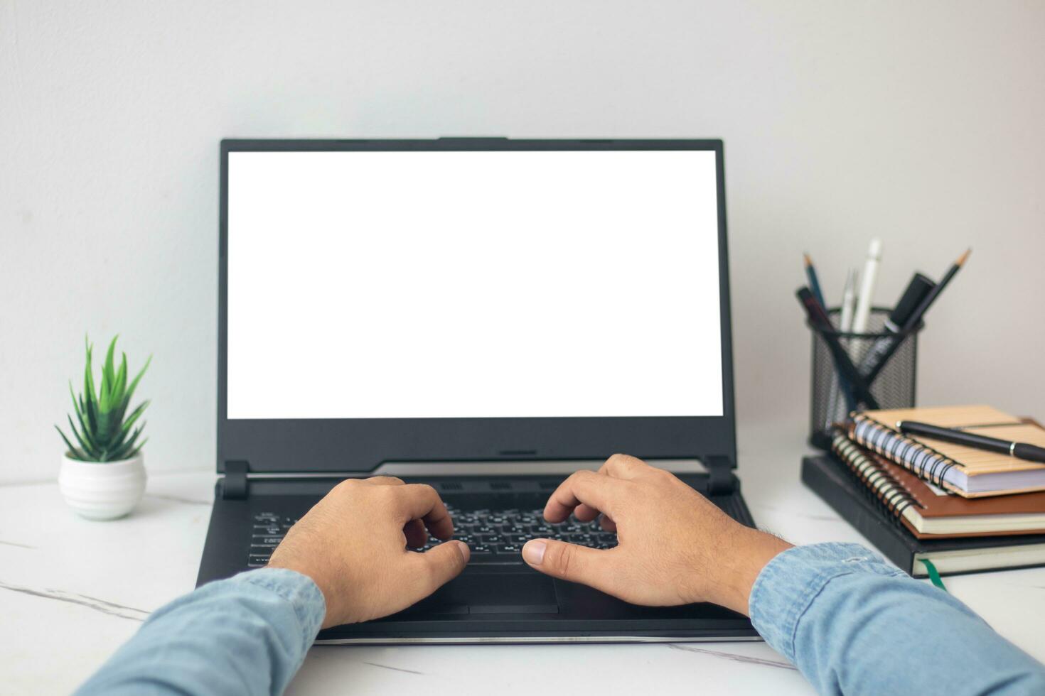 man's hands working on laptop at home desk photo