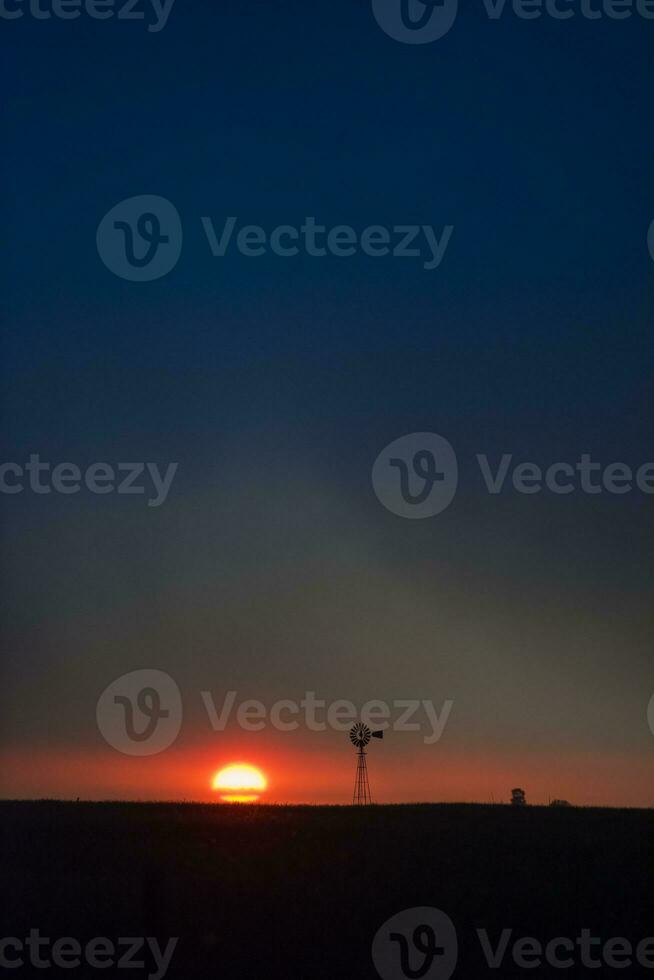 Pampas windmill landscape at sunsetin storm, La Pampa Province,  Argentina photo