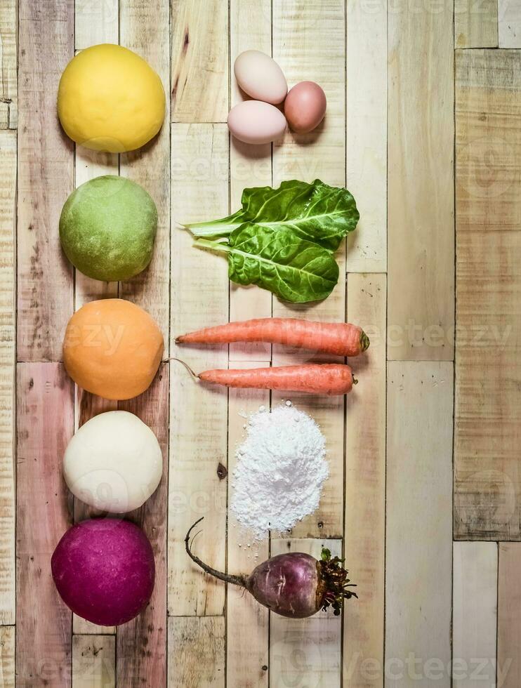 Colored dough buns for pasta, with ingredients on the table. photo