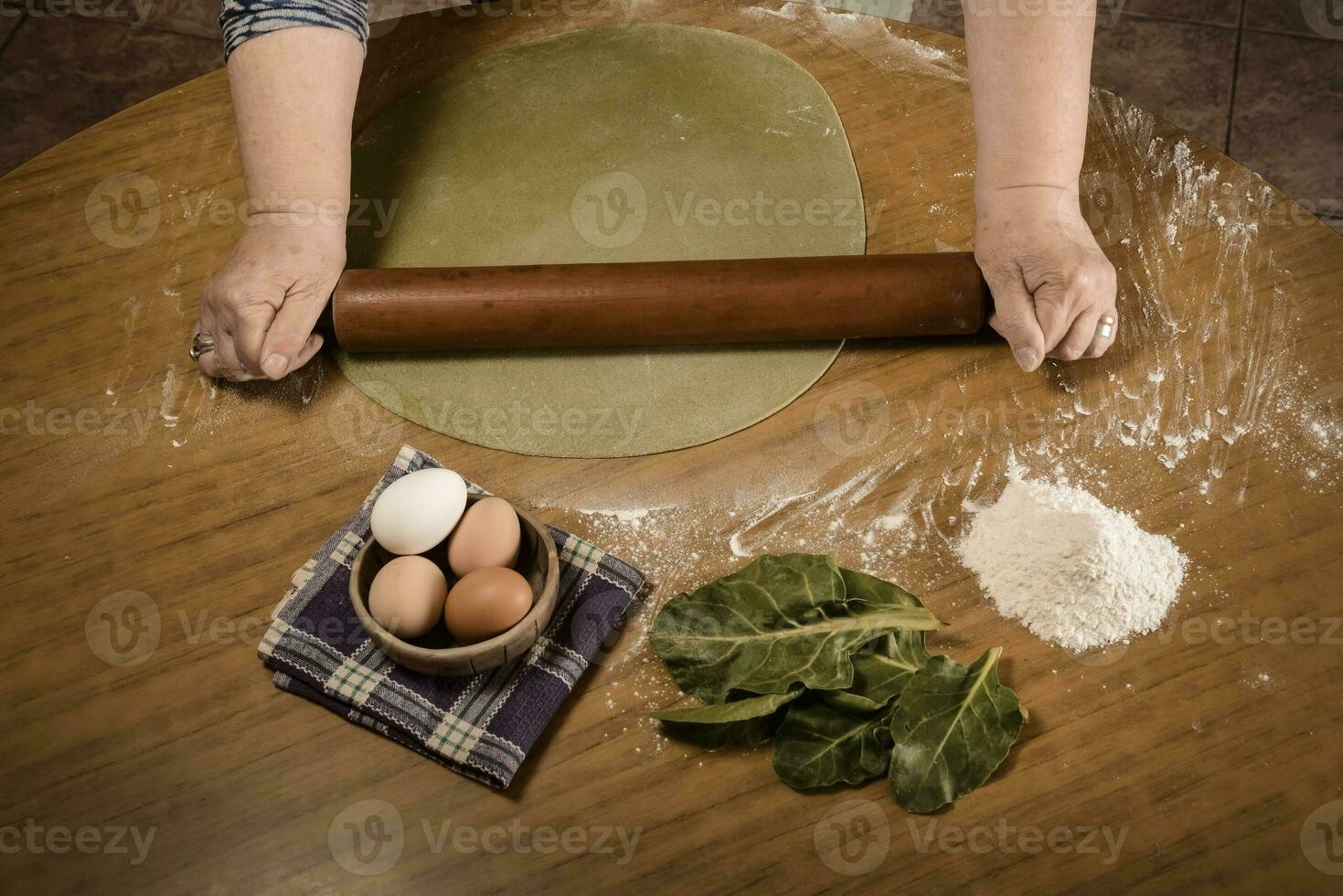 Grandma's hands kneading, dough for green noodles. photo