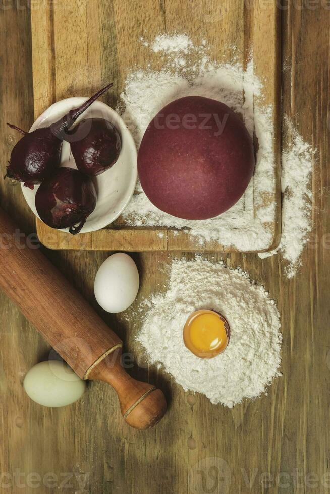 púrpura masa bollo para tallarines con ingredientes en el mesa. foto