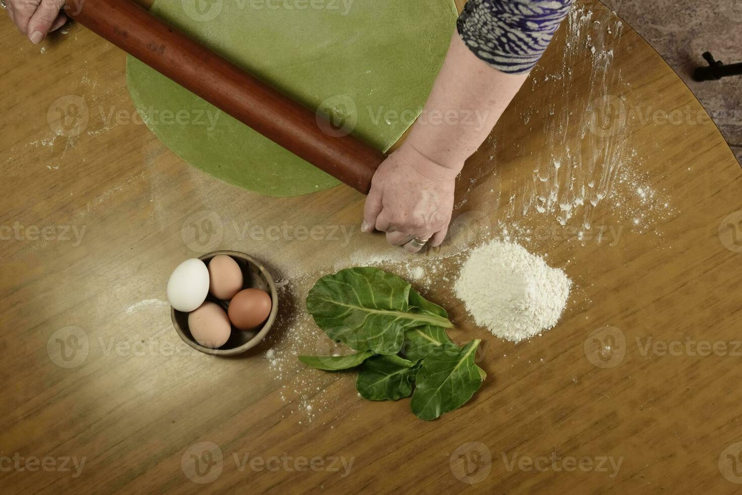 Grandma's hands kneading, dough for green noodles. photo