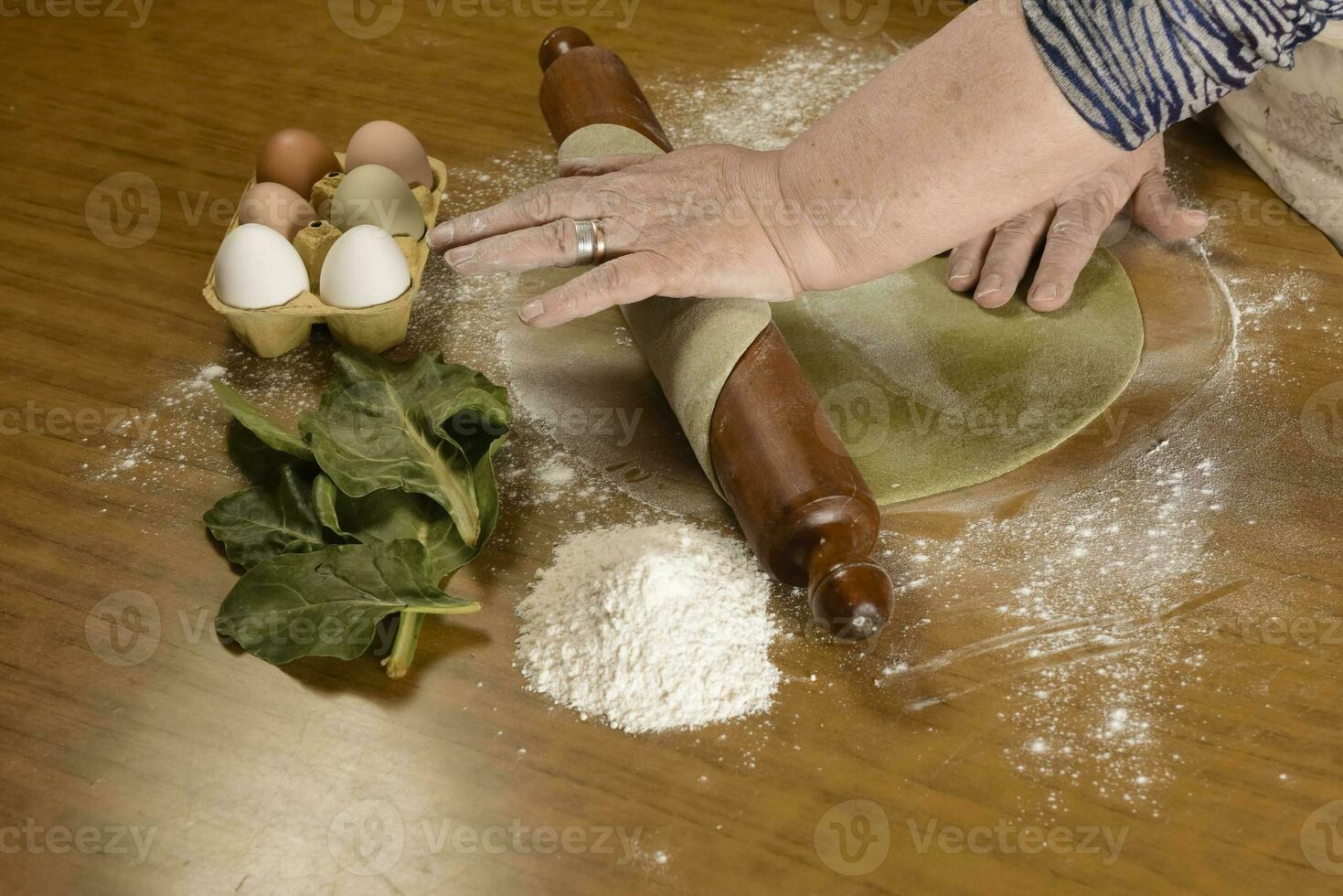 Grandma's hands kneading, dough for green noodles. photo