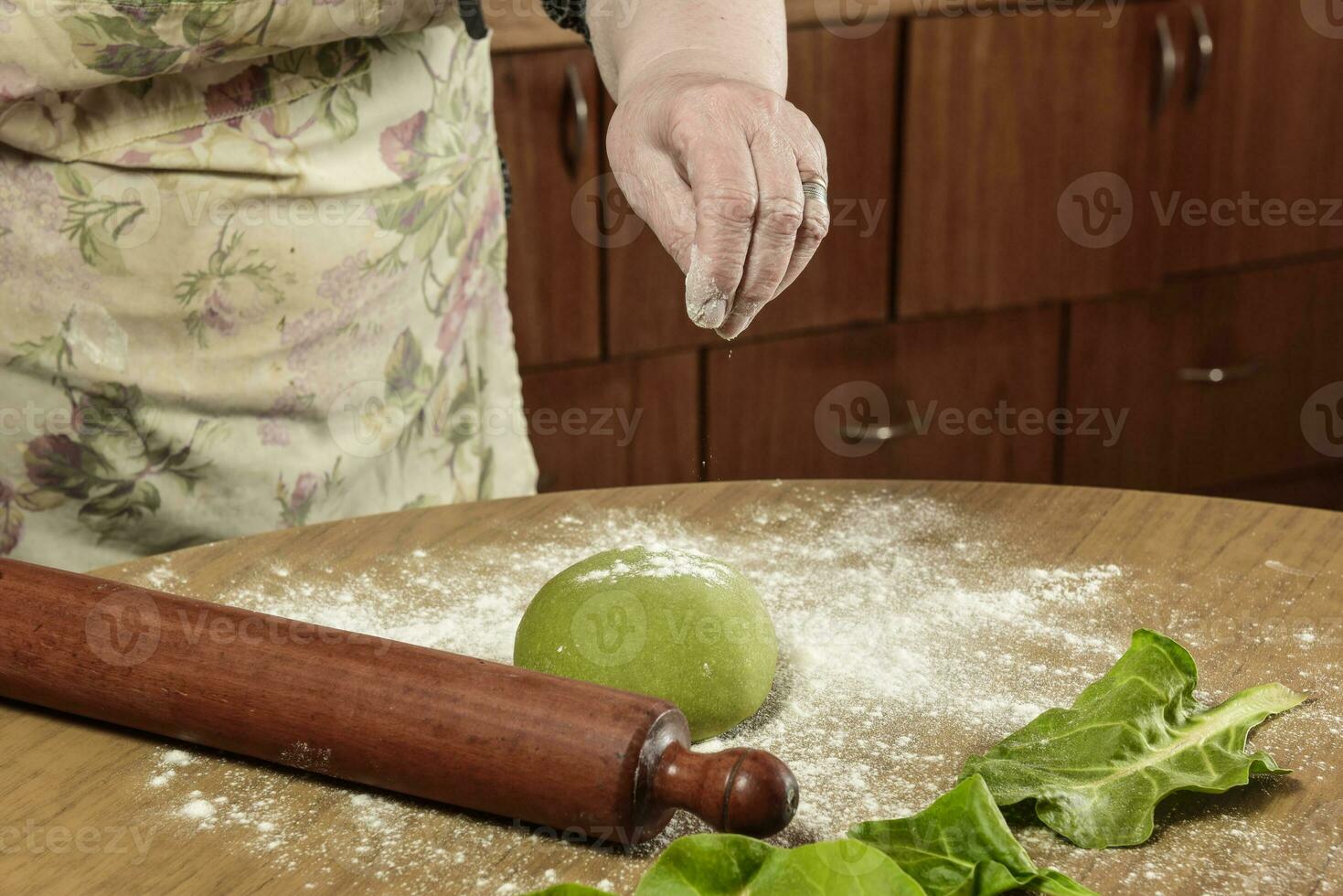 Grandmother hands kneading green dough for noodles in the kitchen. photo