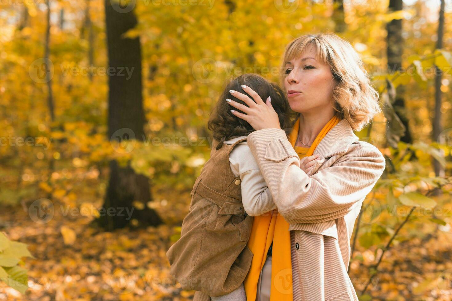 madre calma su llorando rubia hija. mamá sostiene tristeza bebé en su brazos en otoño naturaleza. foto
