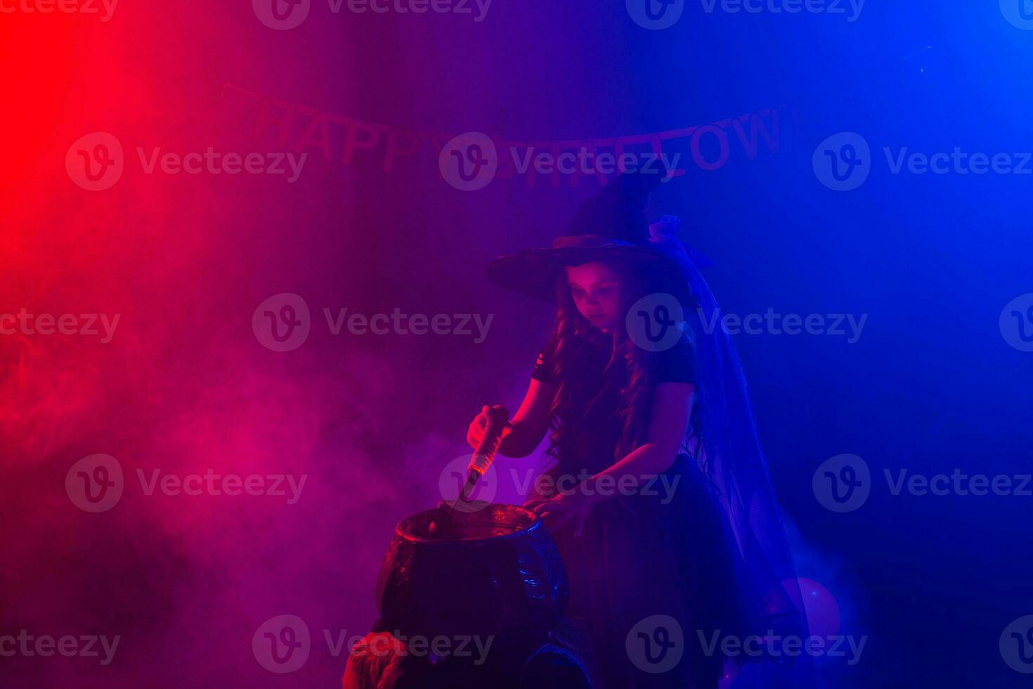 Little witch child cooking potion in the cauldron on Halloween. photo