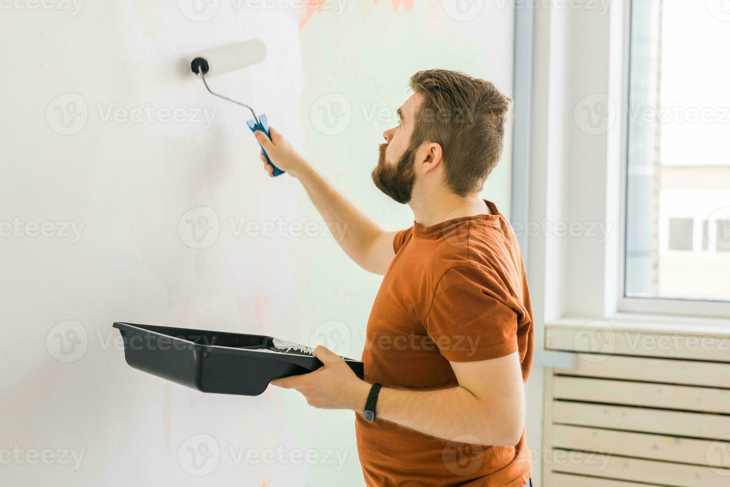 hombre pintura pared con pintar rodillo - renovación y redecoración concepto foto
