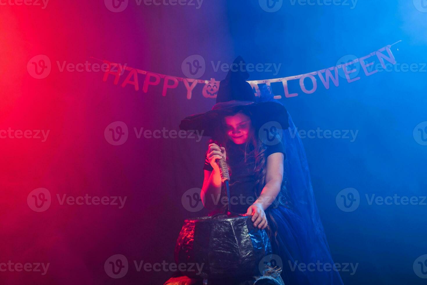 Little witch child cooking potion in the cauldron on Halloween. photo