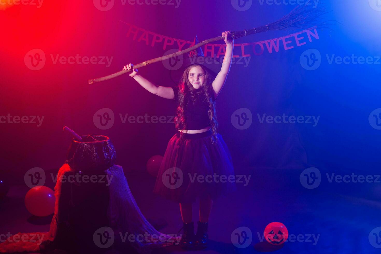 Little girl holds broom on Halloween holiday. Kid girl wear witch costume. Fantasy, fairy tale and masquerade concept. photo