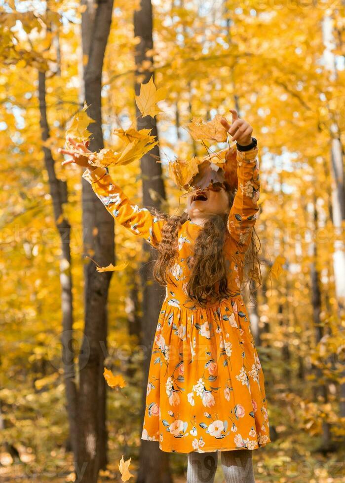 contento niño niña lanza otoño hojas y se ríe al aire libre - otoño y temporada concepto foto