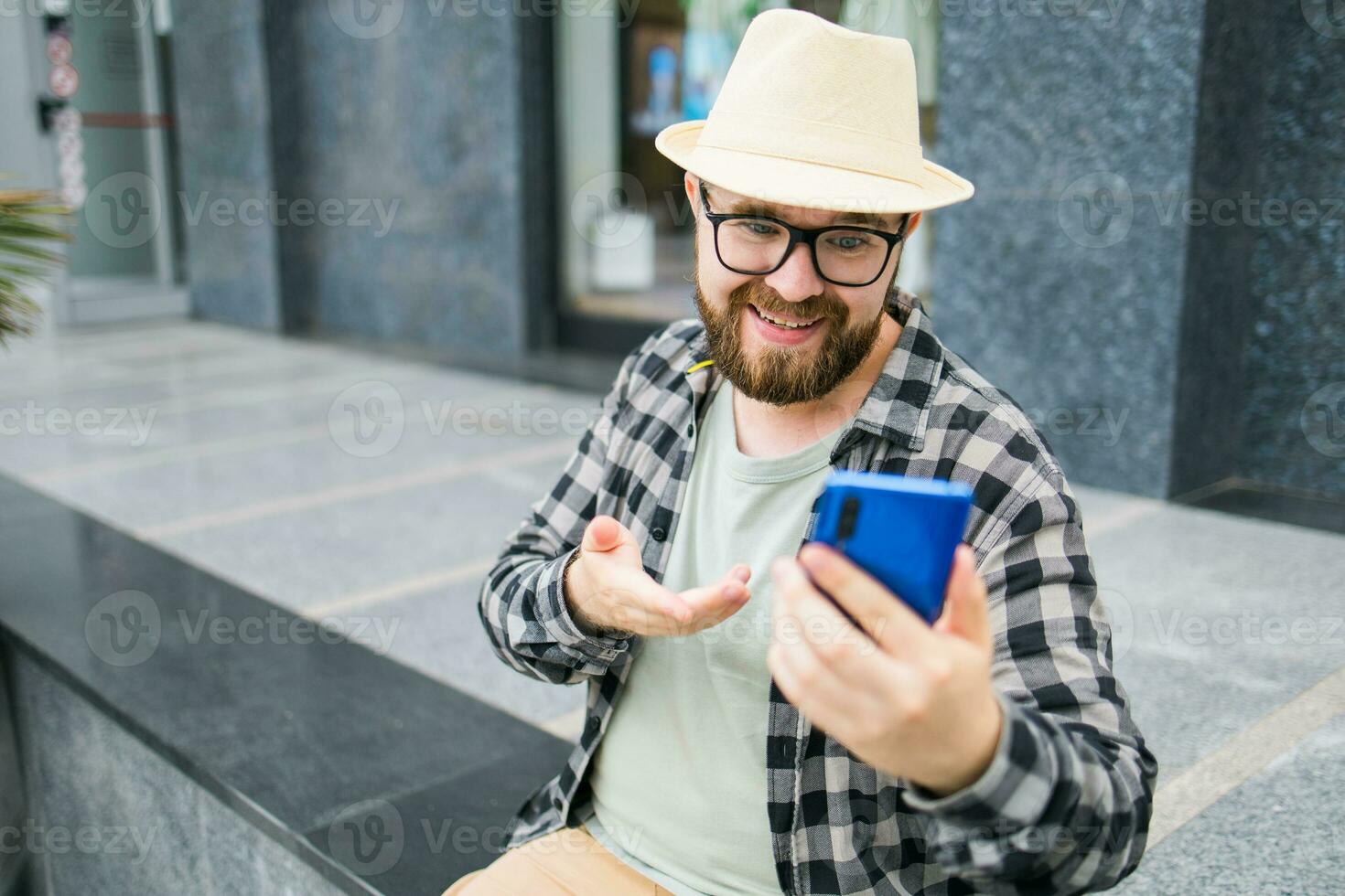 Bearded man doing video call on smartphone outdoor - video connection and technologies concept photo