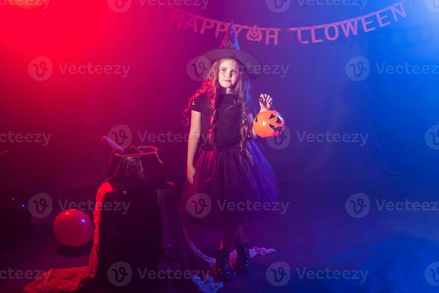 Little girl holds pumpkin jack on Halloween holiday. Kid girl wear witch costume. Fantasy, fairy tale and masquerade concept. photo