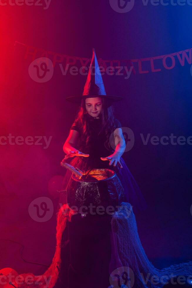 Little witch child cooking potion in the cauldron on Halloween. photo