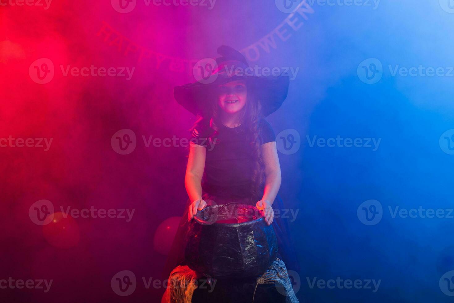 Child girl witch preparing a potion in the cauldron at halloween holidays. photo