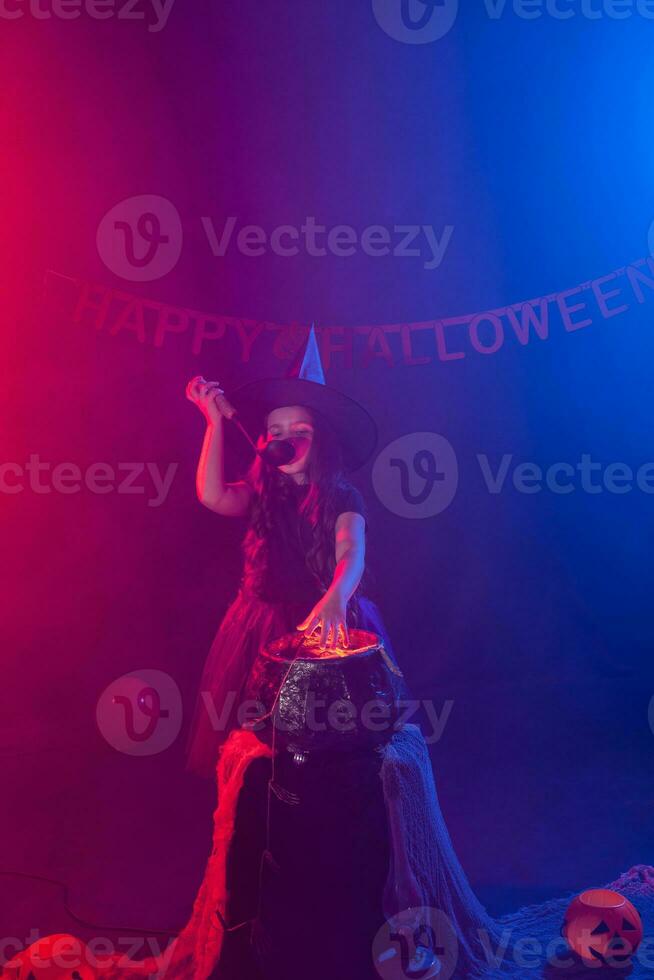 Little witch child cooking potion in the cauldron on Halloween. photo