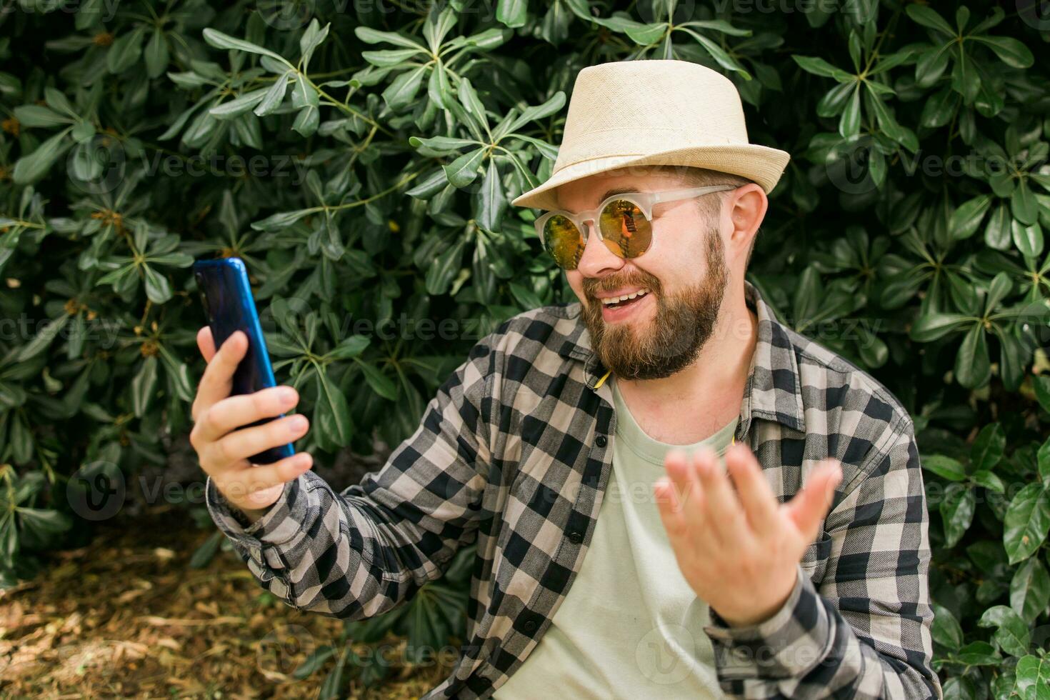 Bearded man doing video call on smartphone outdoor - video connection and technologies concept photo
