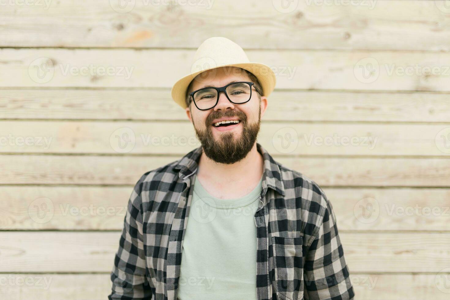 Laughing attractive man wearing hat over wooden background - emotion and vacation travel holidays concept photo