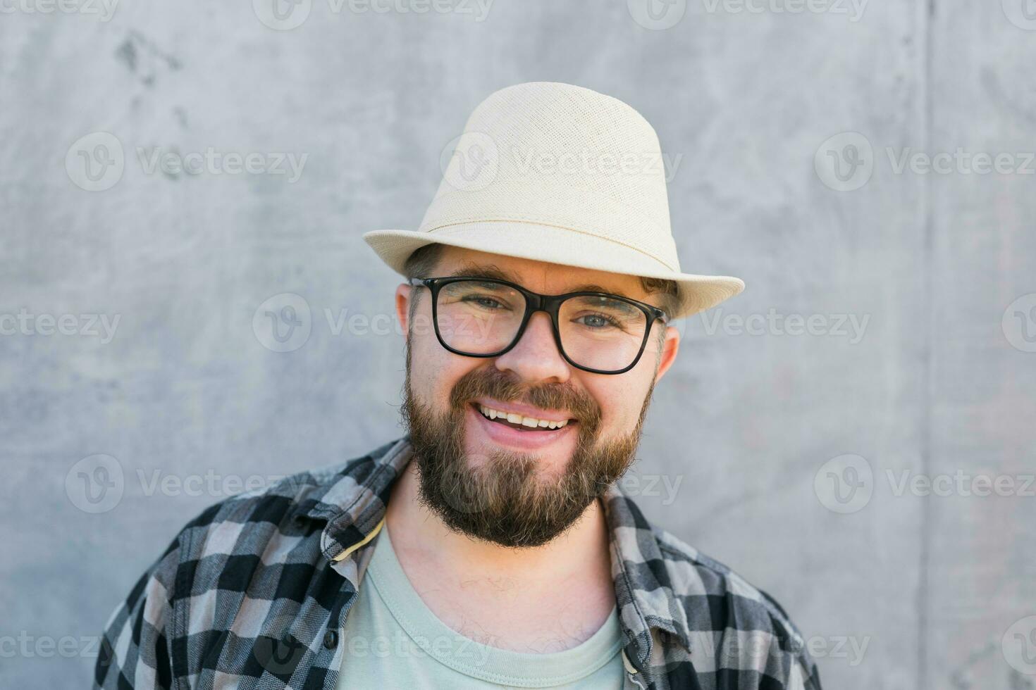Handsome man tourist portrait looking happy wearing straw hat for travelling, standing against concrete wall background photo