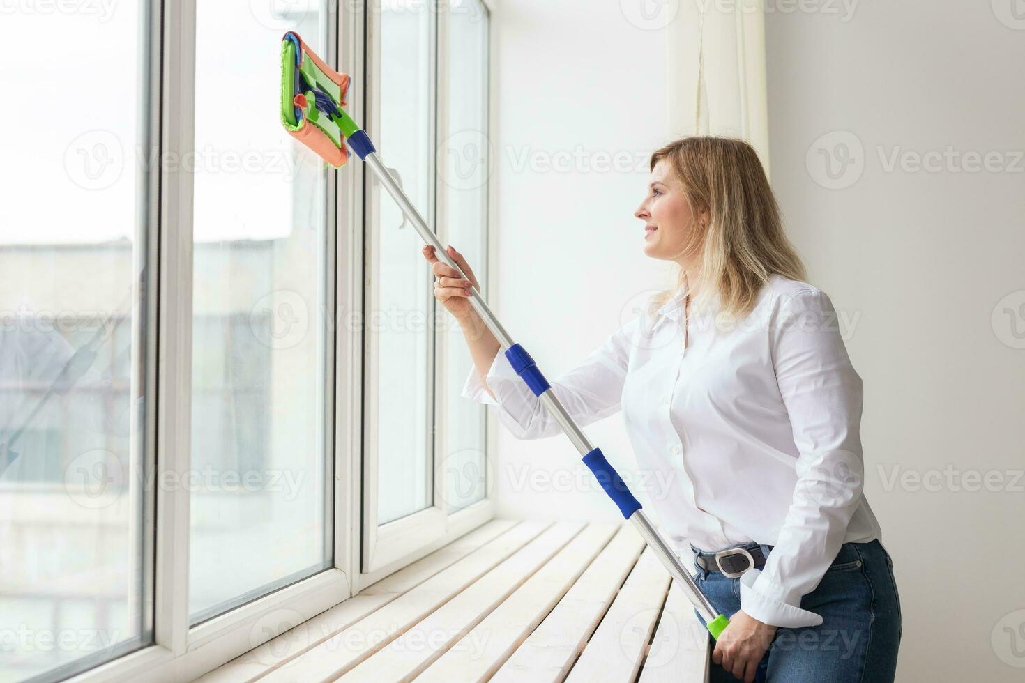 Washing window with special mop and cleaning services - housework and housewife concept photo