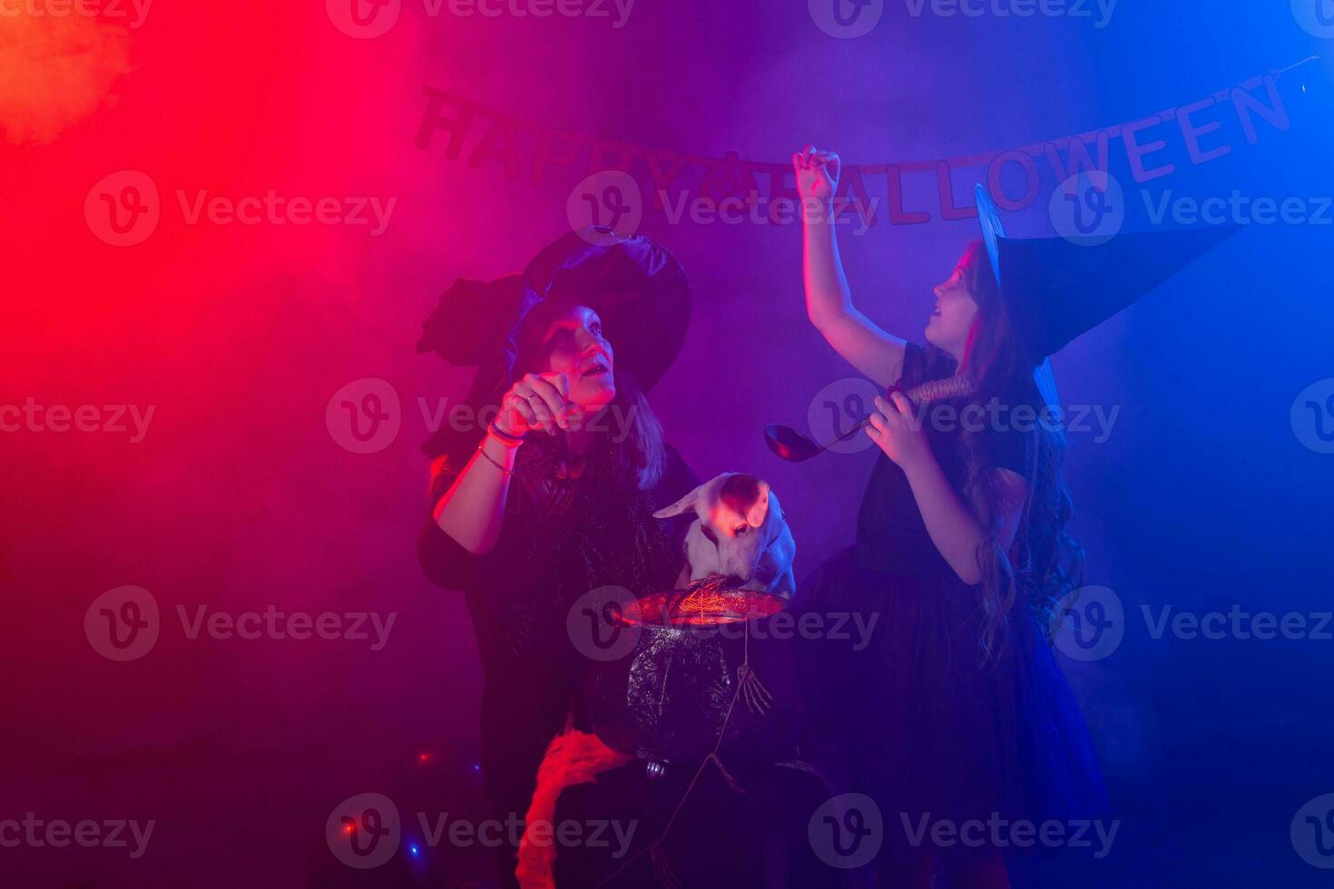 Funny child girl and woman in witches costumes for Halloween with dog. photo