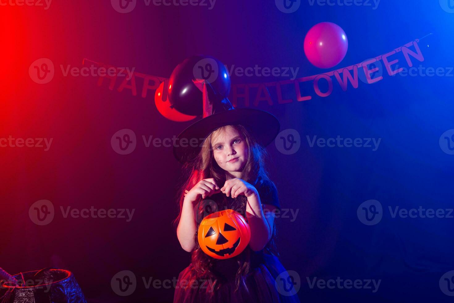 Funny child girl in witch costume for Halloween with pumpkin Jack. photo