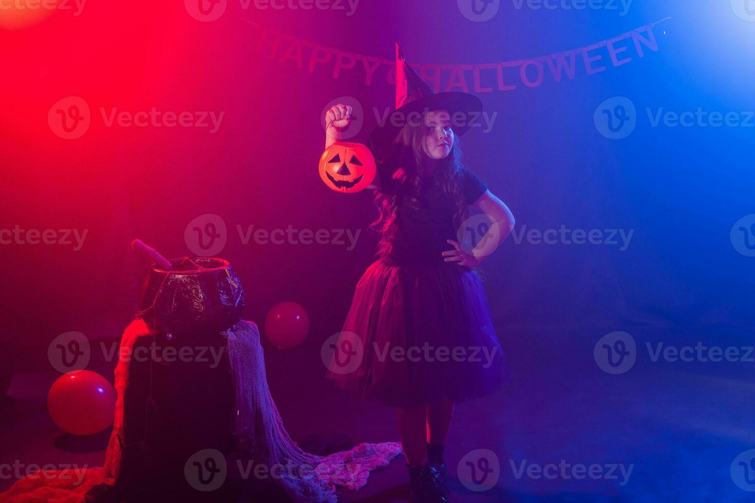 pequeño niña sostiene calabaza Jack en Víspera de Todos los Santos día festivo. niño niña vestir bruja traje. fantasía, hada cuento y mascarada concepto. foto