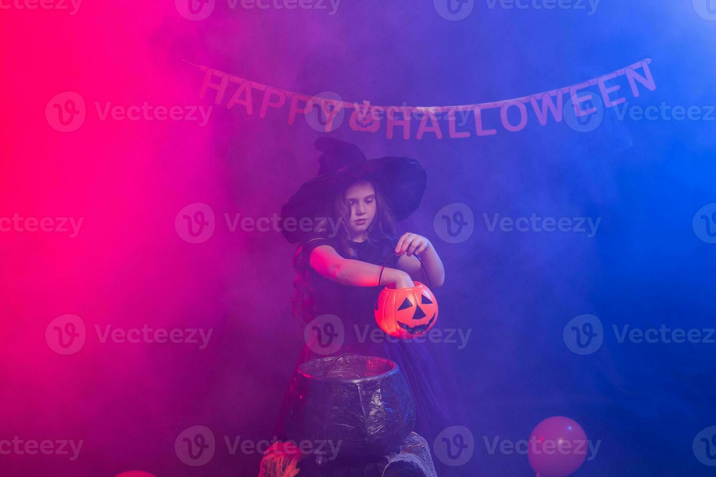 Funny child girl in witch costume for Halloween with pumpkin Jack. photo