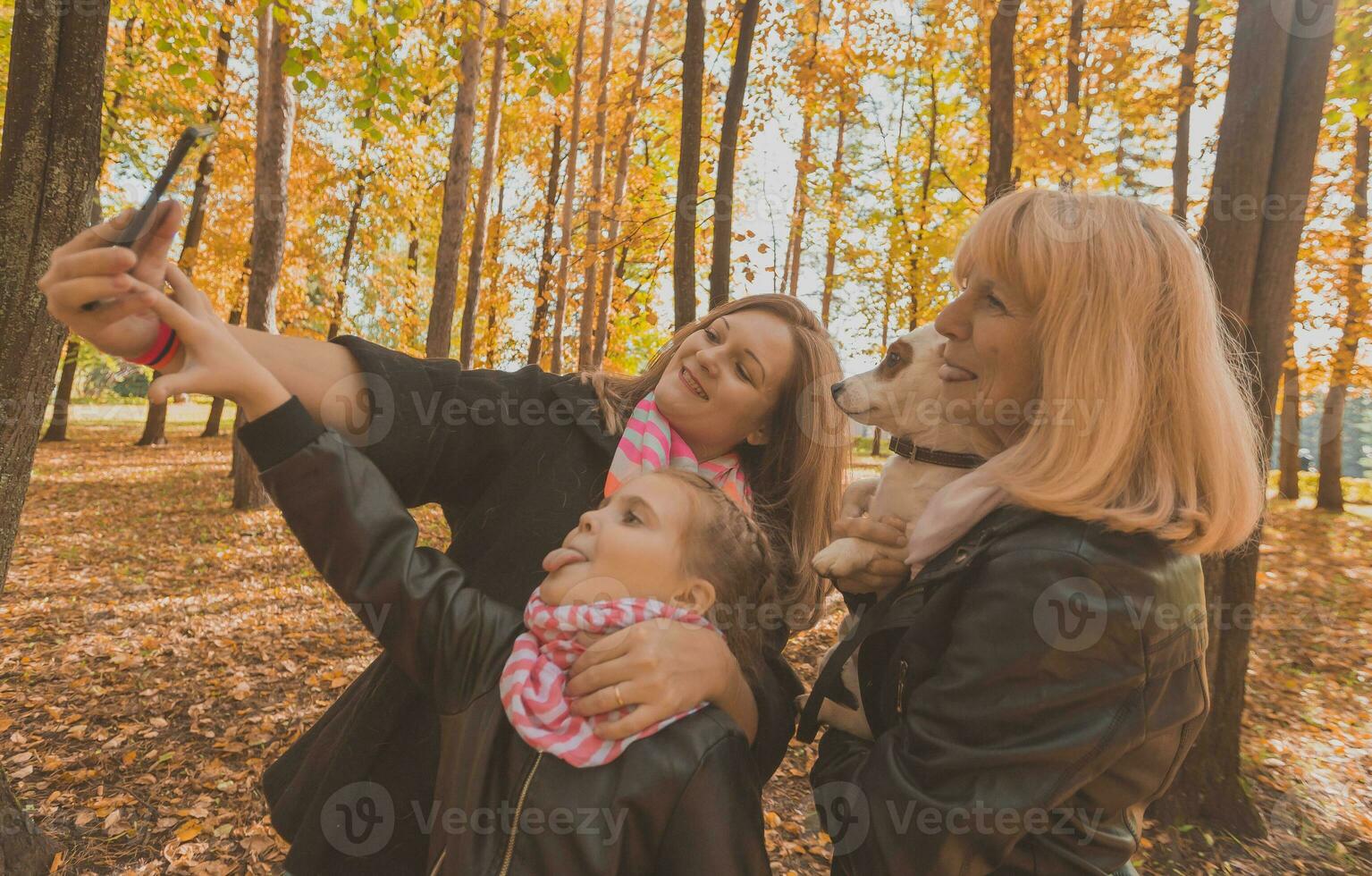 Three generations of women and dog feel fun look at camera posing for self-portrait picture together, funny excited child, mom and grandmother have fun enjoy weekend take selfie on gadget in autumn photo