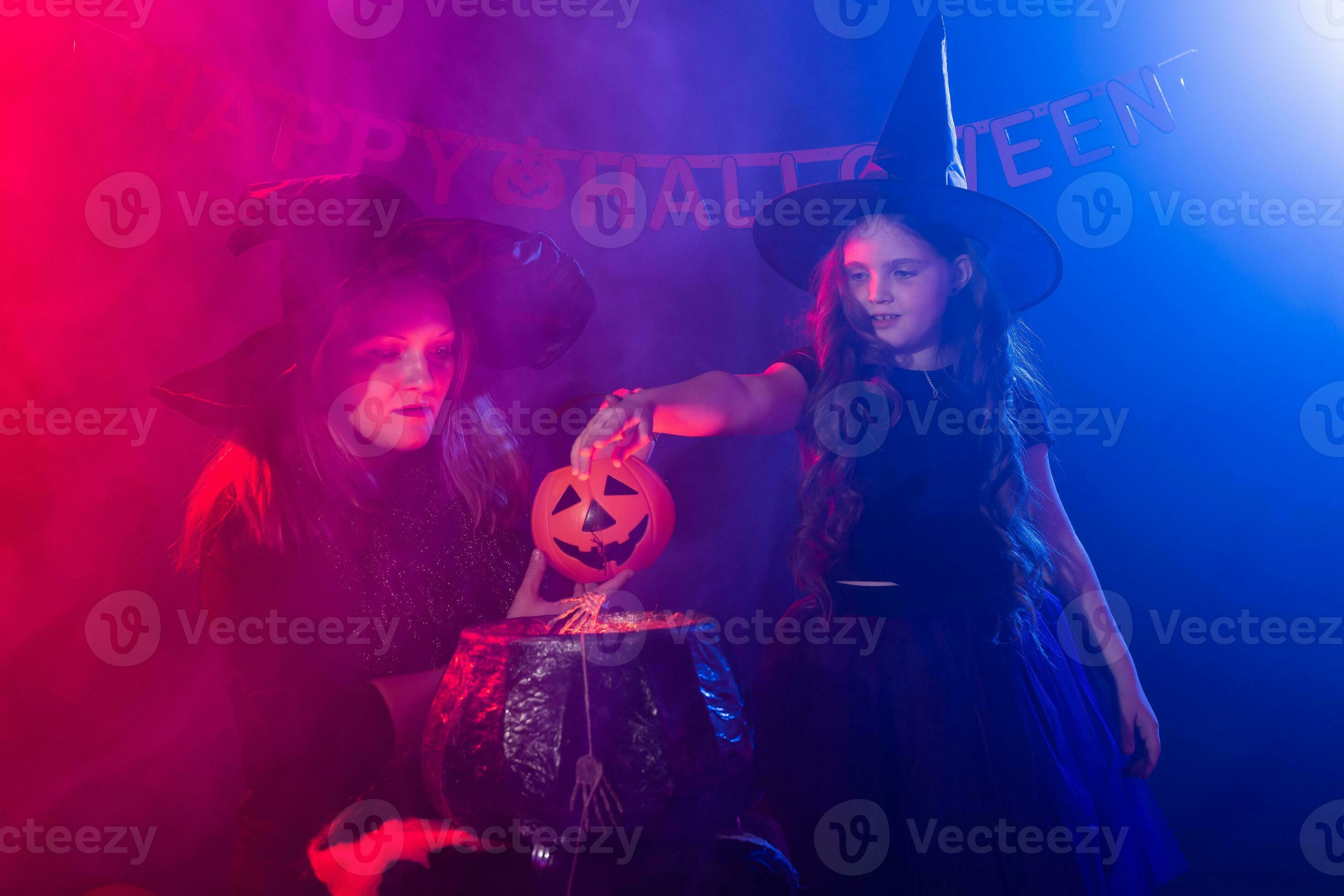 Funny child girl and woman in witches costumes for Halloween with
