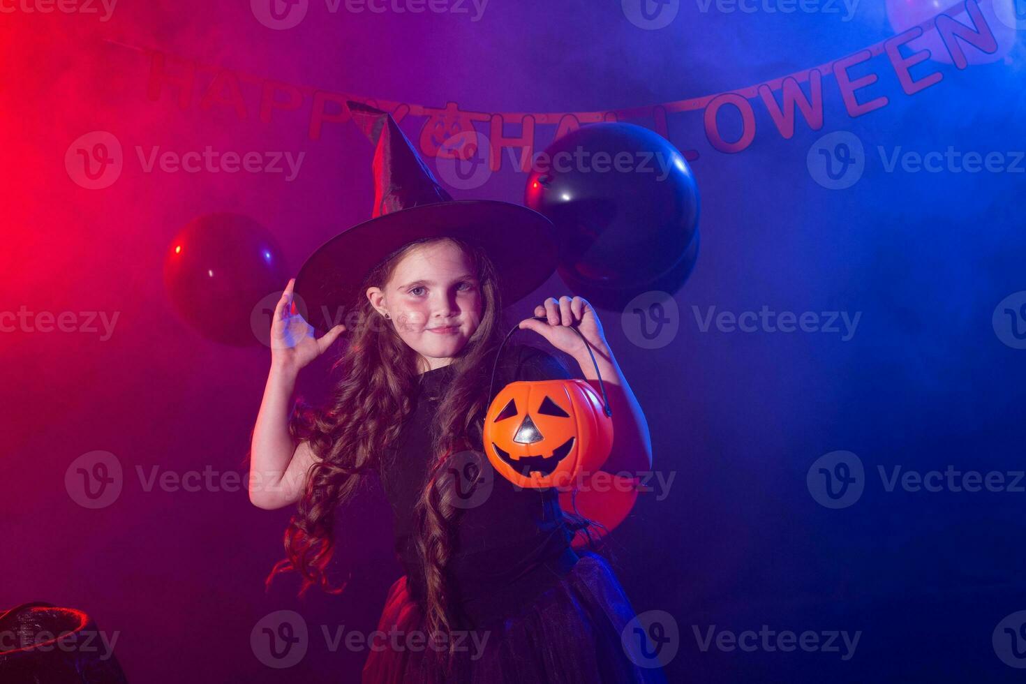 Funny child girl in witch costume for Halloween with pumpkin Jack. photo