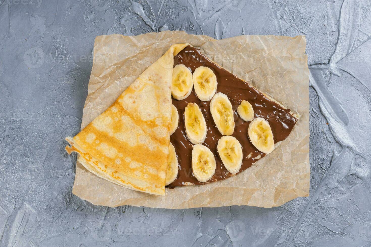 Crepes stuffed with chocolate spread and banana. Thin pancakes. Sweet dessert. French cuisine top view photo