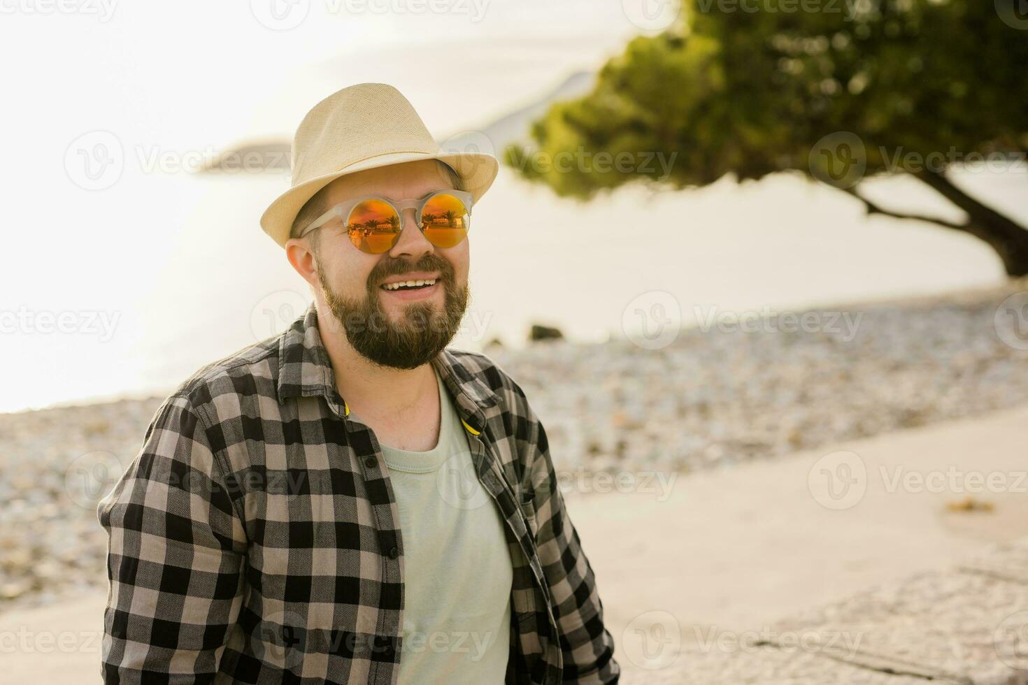 Handsome and confident. Outdoor portrait of smiling man wearing hat and sunglasses on beach copy space and place for text. Holidays travel and summer tourism photo