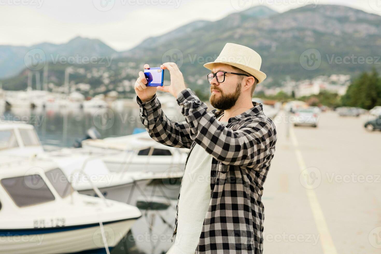 Traveller man taking pictures of luxury yachts marine during sunny day - travel and summer concept photo