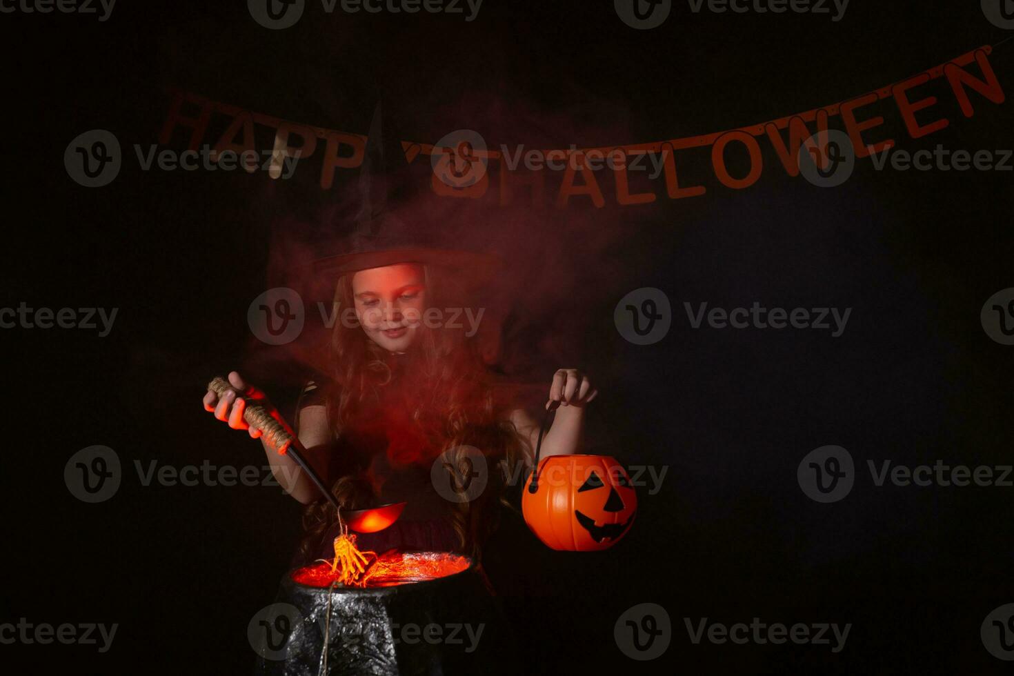 Child girl witch preparing a potion in the cauldron at halloween holidays. photo