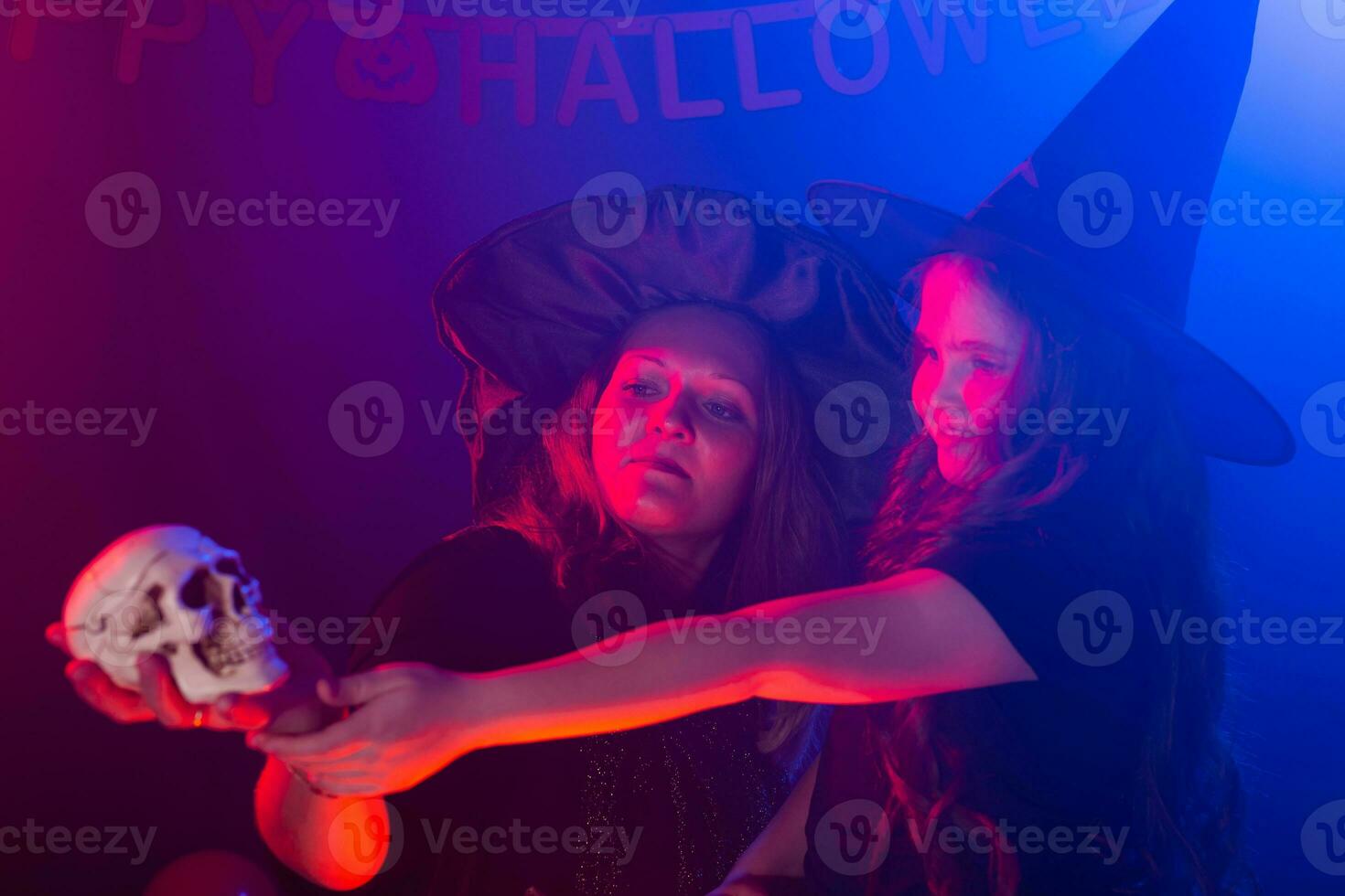 Funny child girl and woman in witches costumes for Halloween making magic. photo