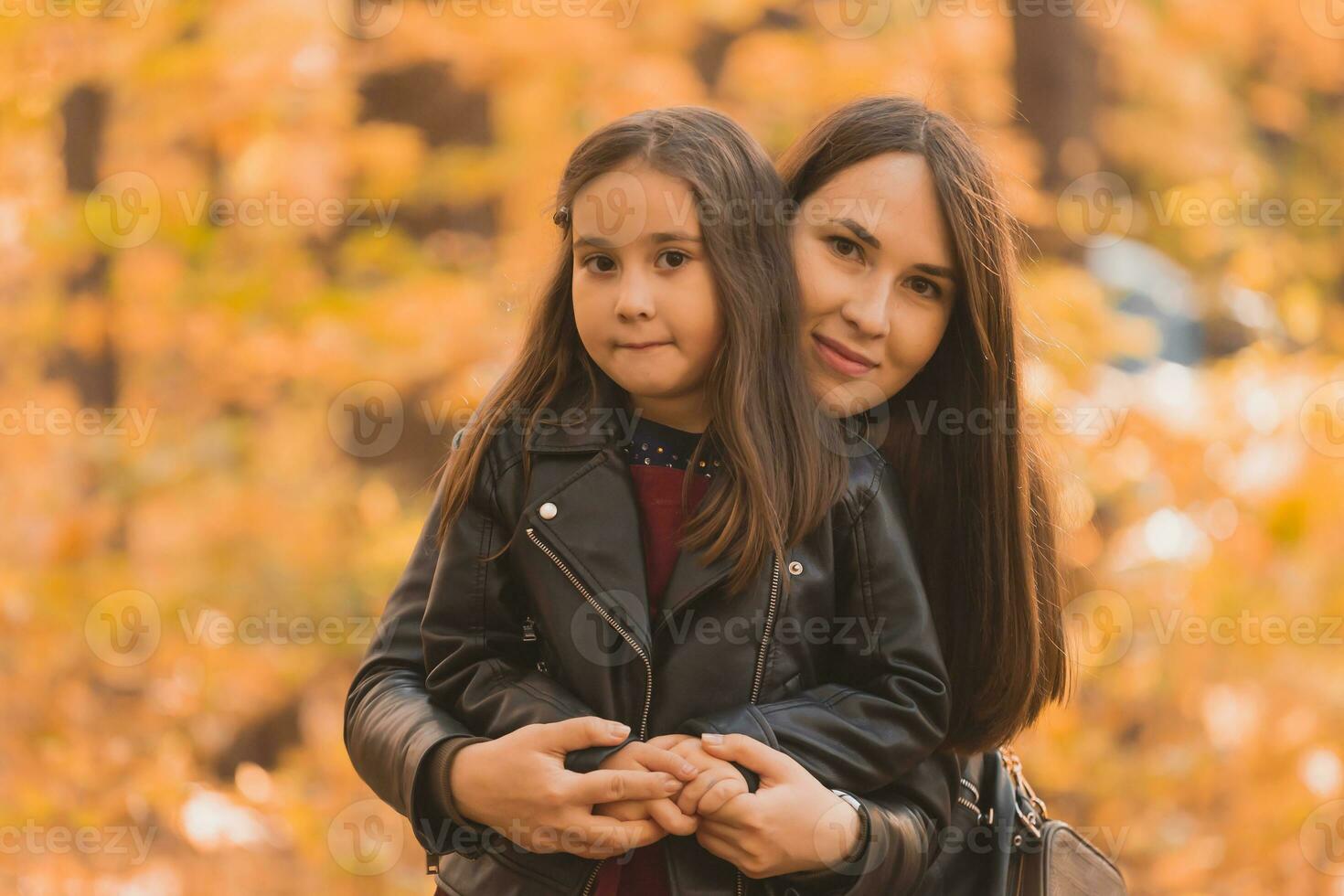 Little girl playing with mother in the autumn park photo