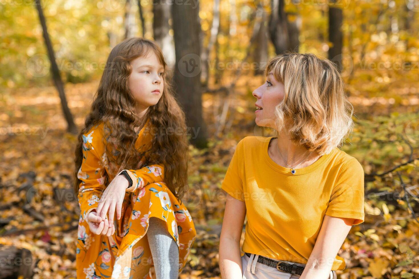 madre calma su infeliz triste hija en otoño naturaleza. niños depresión concepto foto